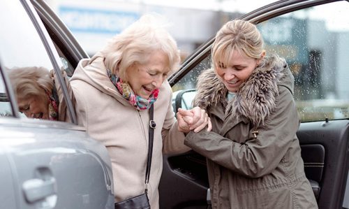 Photo of woman getting out of care with assistance