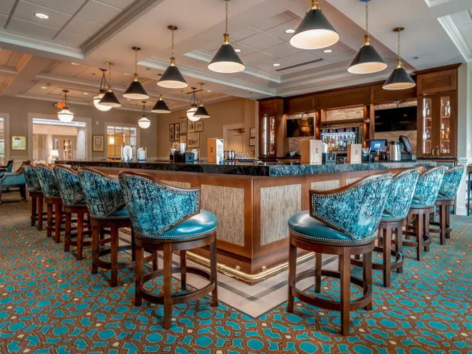 The renovated Cedars Pub featuring a wood bar, teal seating, and warm ambient lighting.